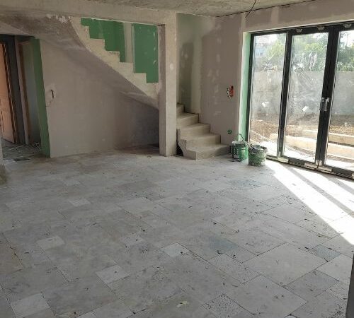 Intérieur de maison avec escalier brut et carrelage posé